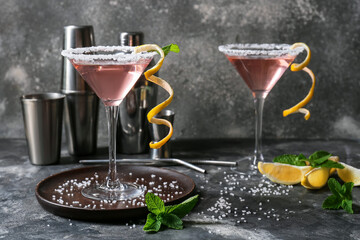 Glasses of tasty cosmopolitan cocktail and shaker on dark background
