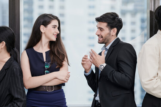 Two happy office colleagues are talking during business seminar break. (Defocused background)