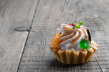 shortcrust pastry with whipped cream and toffees decorated with marmalade on wooden table