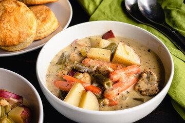 Bowls of Creamy Chicken Stew Served with Biscuits: Chicken and vegetable stew served with biscuits on the side