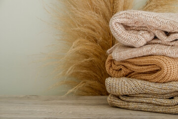 Bunch of knitted warm pastel color sweaters with different knitting patterns folded in stack,...