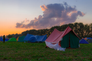 tent camp of a lot of people in festive outdoor environment space in evening dusk time after sunset