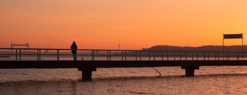 Stroller on the seabridge in Kitzeberg in winter, Kiel skyline , Panorama