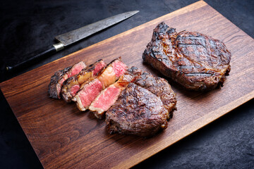 Modern style barbecue dry aged wagyu rib-eye beef steaks served as top view on a wooden design...