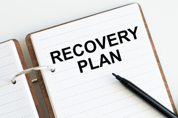 covered notebook with the inscription RECOVERY PLAN on a white background next to a black marker