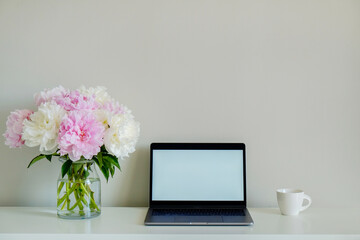 Home office concept. Designated work from home area. Modern laptop and vase with flowers on table....