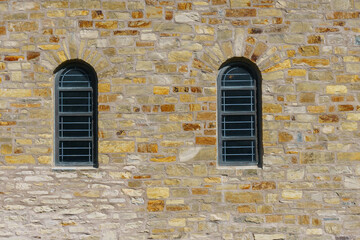 Fototapeta na wymiar Stone wall of an old building with arched windows.