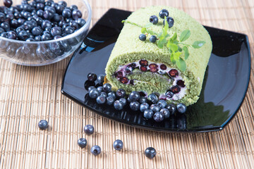 Sponge roll with blueberries and matcha tea. The concept of summer desserts. Selected focus