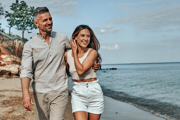Happy attractive couple walking on beautiful sunny beach.