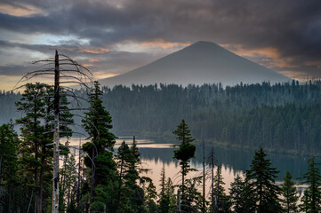 sunrise and a silhouette of Black Butte mountain with Suttle lake and a pine forest near the summit...