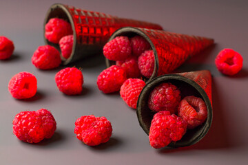 Waffle cones are filled with fresh juicy raspberries on a gray background. View from above. Healthy food concept. Low key. Close-up.