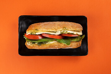 sandwich on ciabatta bread with white cheese, rucula, tomato and pesto sauce