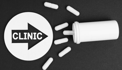 Pills on a black background. They are indicated by a circle with an arrow, inside which it is written - CLINIC