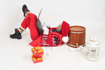 Santa Claus lies on the floor and communicates online via a laptop.