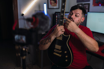 Chico joven gordo con camiseta roja grabando frente a una cámara en un set up gamer
