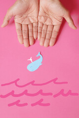 Fish-shaped paper, empty on hand, isolated from pink background.