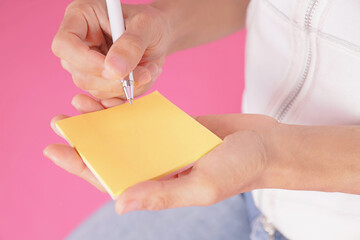 woman writing message on yellow note paper.