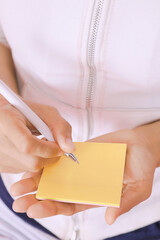 woman writing message on yellow note paper