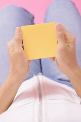 hand holding yellow note paper.on the pink background isolate