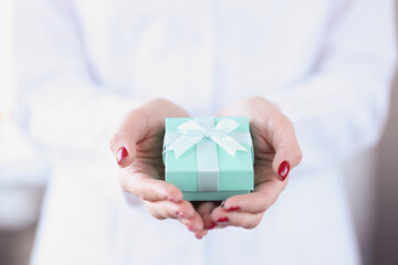 Small turquoise gift box in female hands closeup