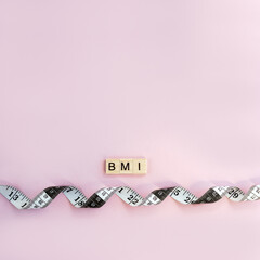 Word BMI on wooden blocks with letters and measuring tape on pastel background. Control concept...