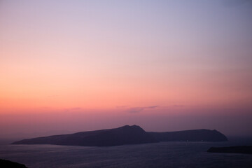 Serene island silhouette against a pastel sunset over the calm sea.