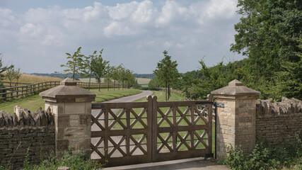 Obraz premium Looking down a driveway through ornate wooden gates