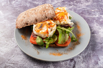 Poached egg sandwich. The eggs are sprinkled with a variety of spices. Sandwich on a plate.