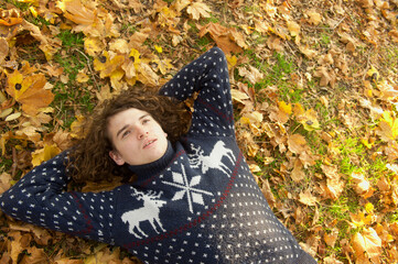 Calm teen man laying on back oudoor in autumn park