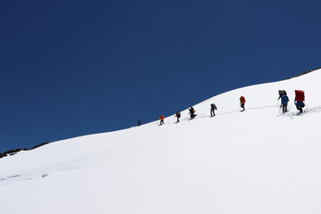 a group of people-tourists overcome the glacier at the mountain pass. Traveling with friends, hiking with a large company. Extreme vacation in the mountains.