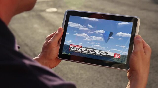 A man watches breaking news of a UFO seen over Western Pennsylvania on his tablet PC. Fictional news report.  	