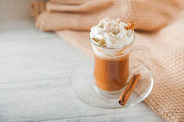 Pumpkin coffee in transparent cup and whipped cream with cinnamon. Autumn cappuccino or latte menu.