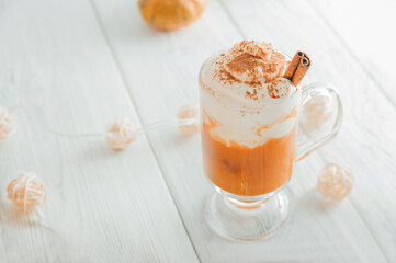Pumpkin coffee in transparent cup and whipped cream with cinnamon. Autumn cappuccino or latte menu.