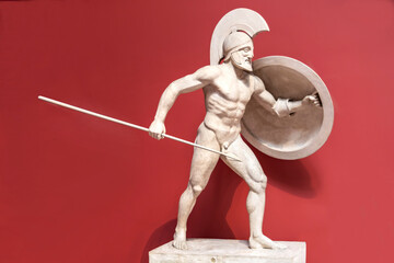 a stone sculpture of a Roman soldier with a spear and shield. The concept of strength, courage. Red background