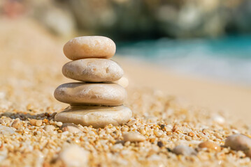 Fototapeta na wymiar Pyramid stones balance on the sand of the beach. Zen balance, minimalism, harmony and peace