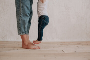 close-up of mom's legs and little daughter on a wooden floor