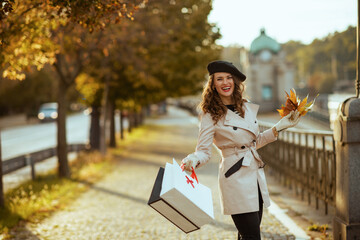 happy stylish female with shopping bags and autumn leaves