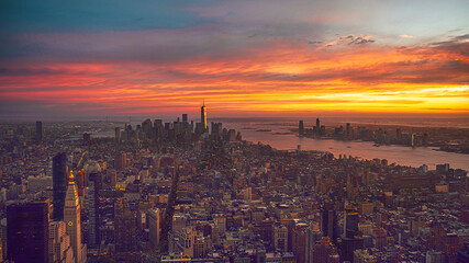view of New York skyline at sunset from midtown Manhattan with harbor and New Jersey in distance.