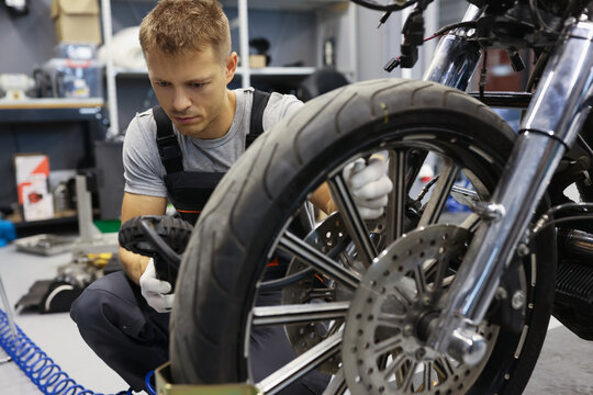 Man Checks Tire Pressure On Motorcycle In Workshop