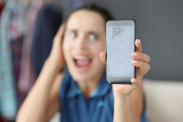 Upset woman holding broken smartphone in hands
