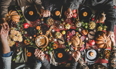 Family or friends praying holding hands at Thanksgiving celebration table - 449954581