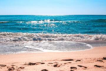 Seascape. A beautiful blue sea sparkling in the sun, running onto the sandy shore. Travel and tourism.