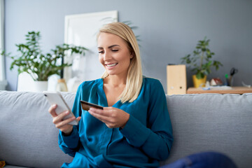Woman using smartphone for online payments sitting on the sofa at home