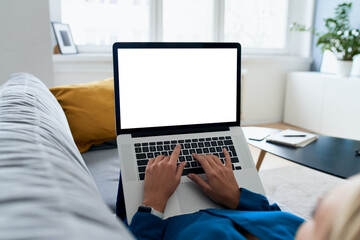 Woman lying on the sofa using laptop with blank screen
