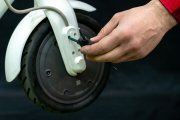 Repair of a modern electric scooter in a professional workshop. In the hands of the mechanic, the tool and the dismantled parts of the scooter are in the hands. Wheel and tire close-up.