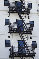 A fire escape stairs and platforms are shown on the side of an old highrise building.