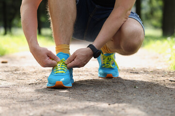 Runner tying running shoes closeup. City man shoelace sneakers