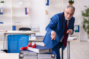 Old male employee with dynamite in the office