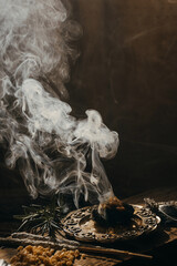 Charcoal burning with incense, incense resin, rosemary, laurel, lavender on a rustic wooden table, 
smudge stick, smudging, energetic cleansing and smoking.Sahumar
