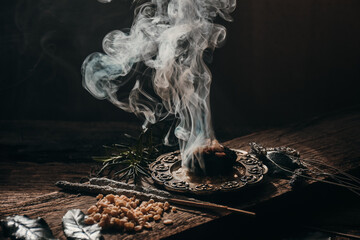 Charcoal burning with incense, incense resin, rosemary, laurel, lavender on a rustic wooden table,...